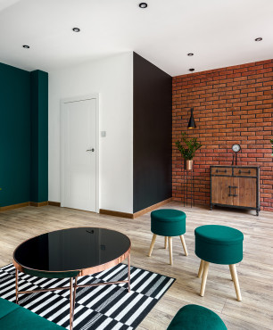 Wohnzimmer mit grünen Möbeln und Backsteinwand