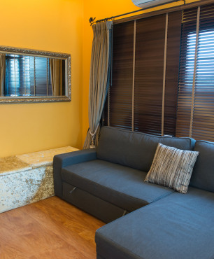 Wohnzimmer mit marineblauem Sofa und gelber Wand