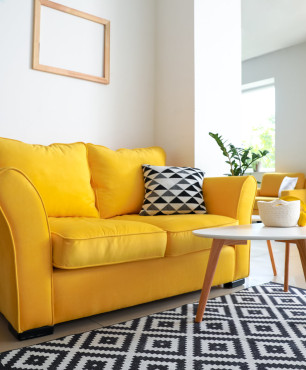 Gelbes Sofa mit schwarz-weißem Vorleger