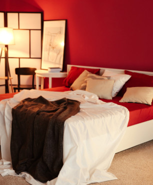 Weißes Bett in einem roten Schlafzimmer